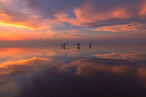 Free Stunning sunset over the reflective waters in Vietnam with vibrant skies and silhouettes of fishermen. Stock Photo