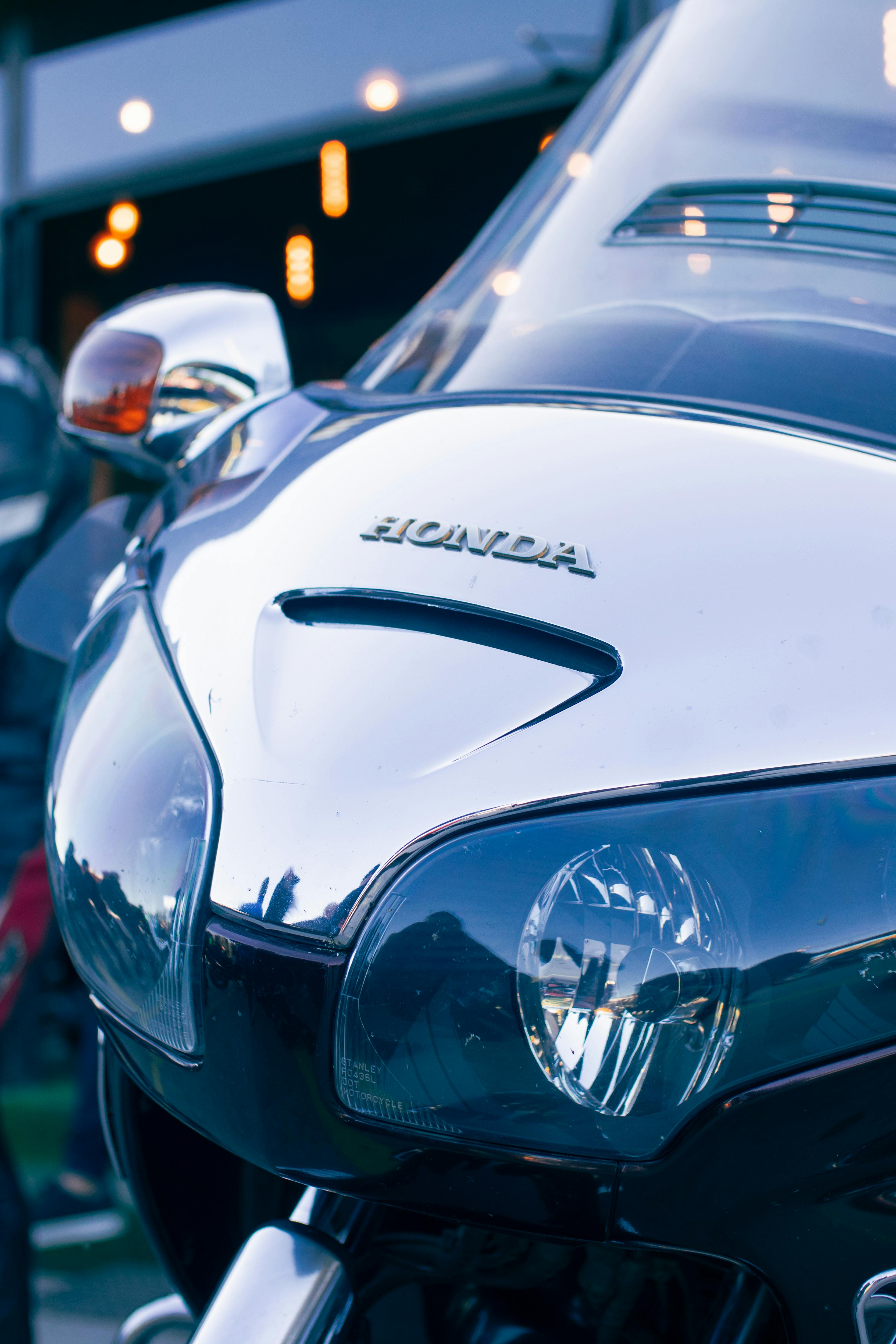 Close-up of a Honda motorcycle front, showcasing its sleek chrome design and dynamic headlight.