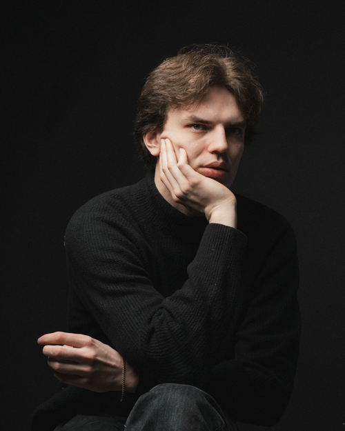 Free Thoughtful young man in a black sweater gazing into the distance in a studio portrait. Stock Photo