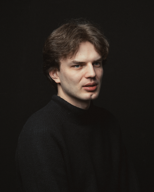 Free Studio portrait of a young man wearing a black sweater against a dark background. Stock Photo