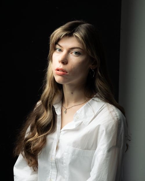 Free A serene portrait of a woman with long hair and a white shirt, captured in soft natural light. Stock Photo