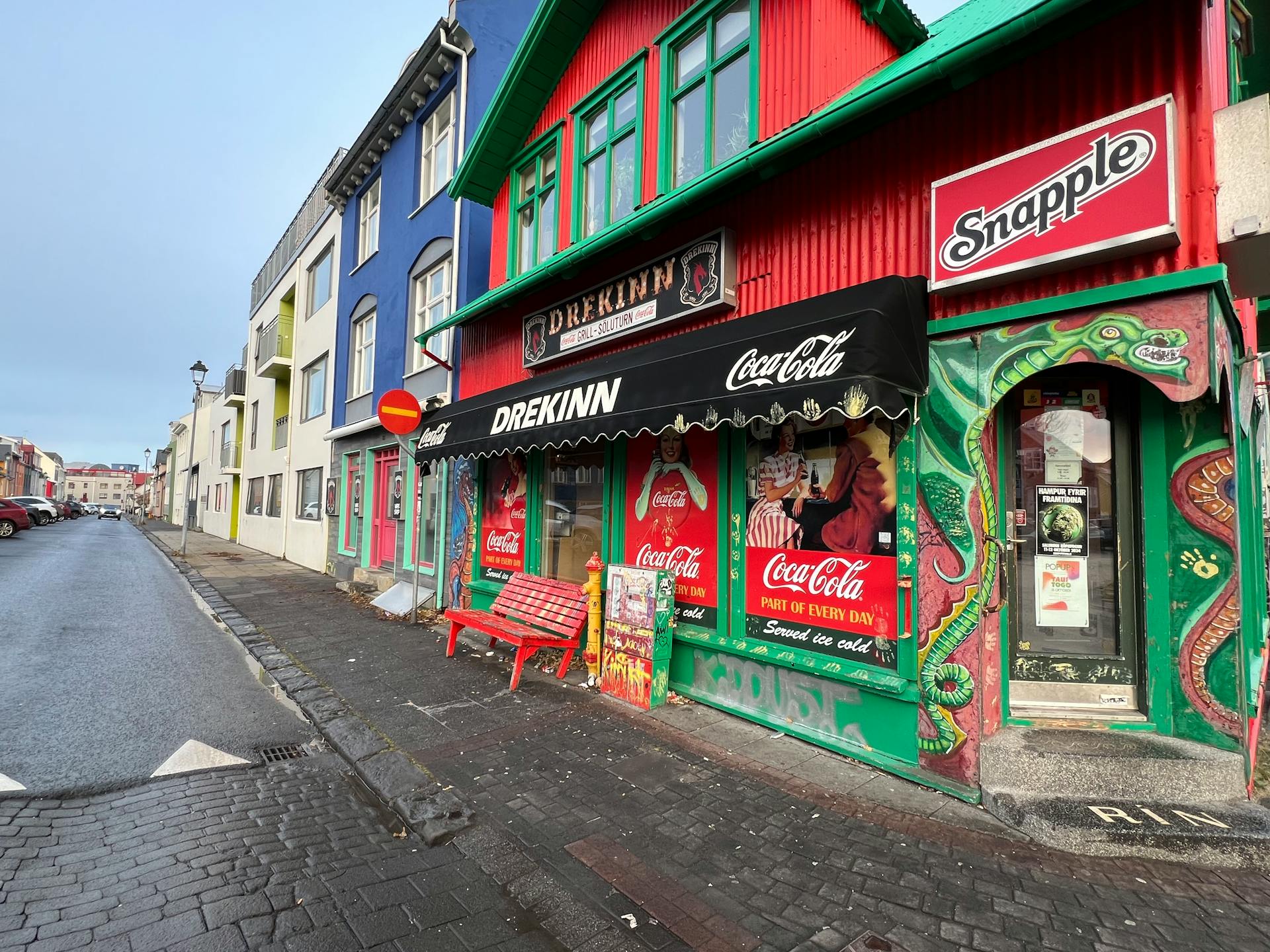 Vibrant storefronts on a street in Reykjavik showcasing colorful architecture and Coca-Cola signage.