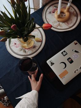 A warm indoor setup with a laptop, tulips, and a coffee cup, perfect for modern workspaces.