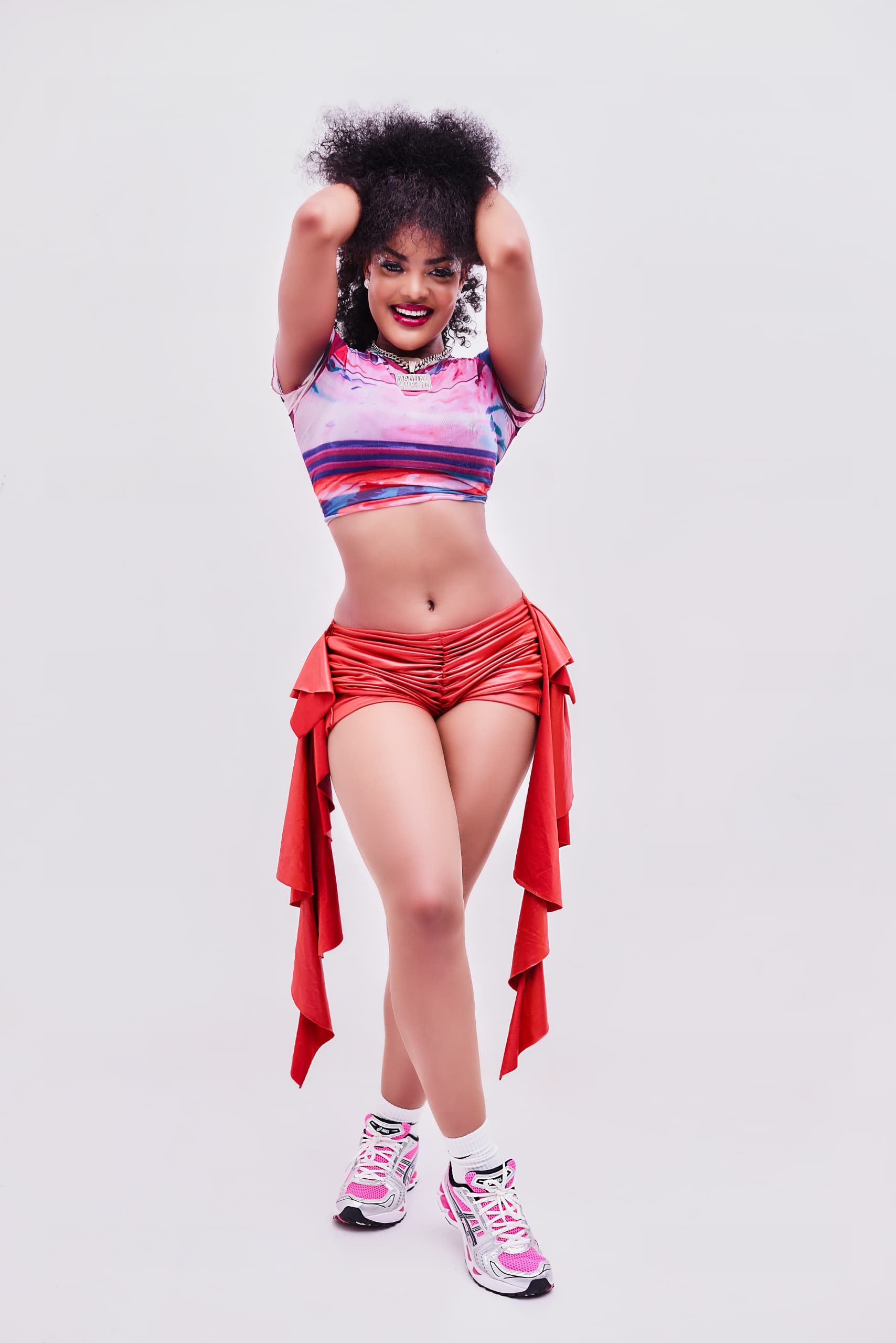 Young woman in colorful fashion, posing with a radiant smile and dynamic attire.