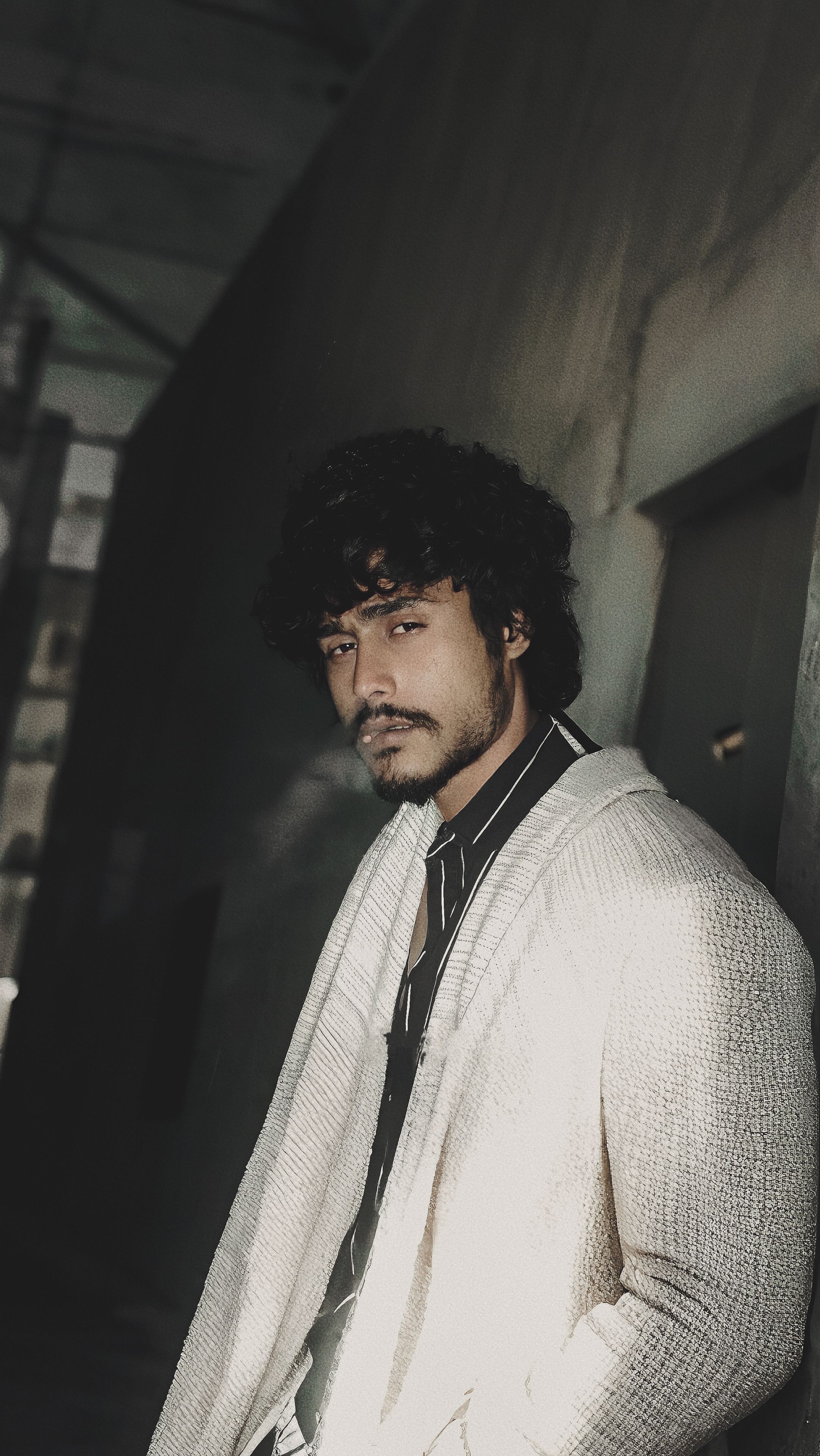 Stylish young man in casual wear posing in moody, urban light. Perfect for fashion and lifestyle concepts.