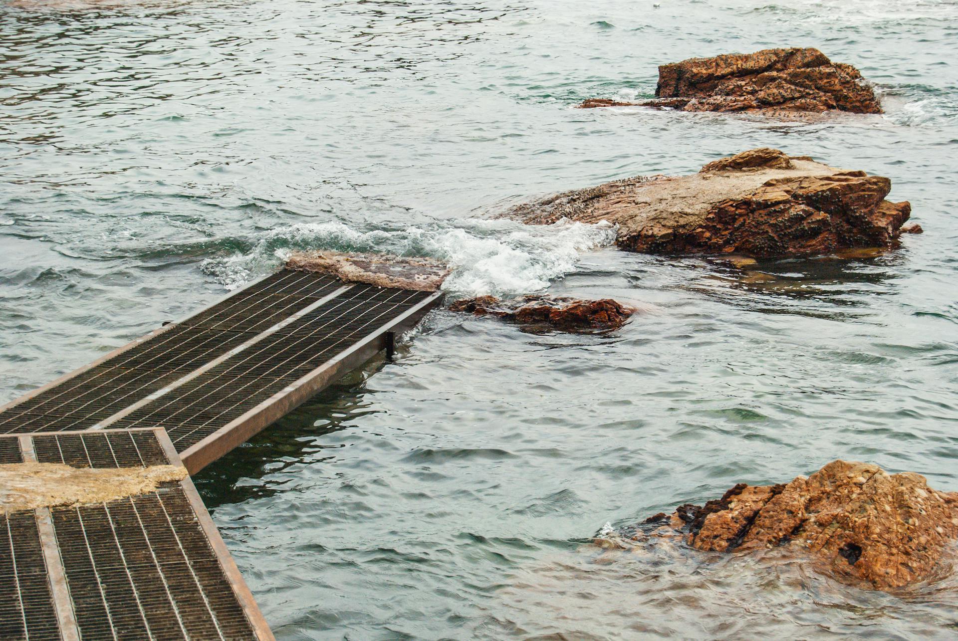 Tranquil scene of coastal rocks and a pier at Shenzhen seaside with gentle waves crashing.