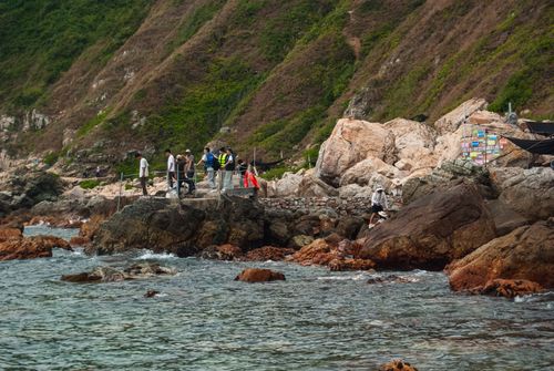 Free A scenic view of a rocky coastline in Shenzhen with people enjoying the seaside setting. Stock Photo