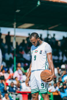Basketball player in concentration on court during intense outdoor match.