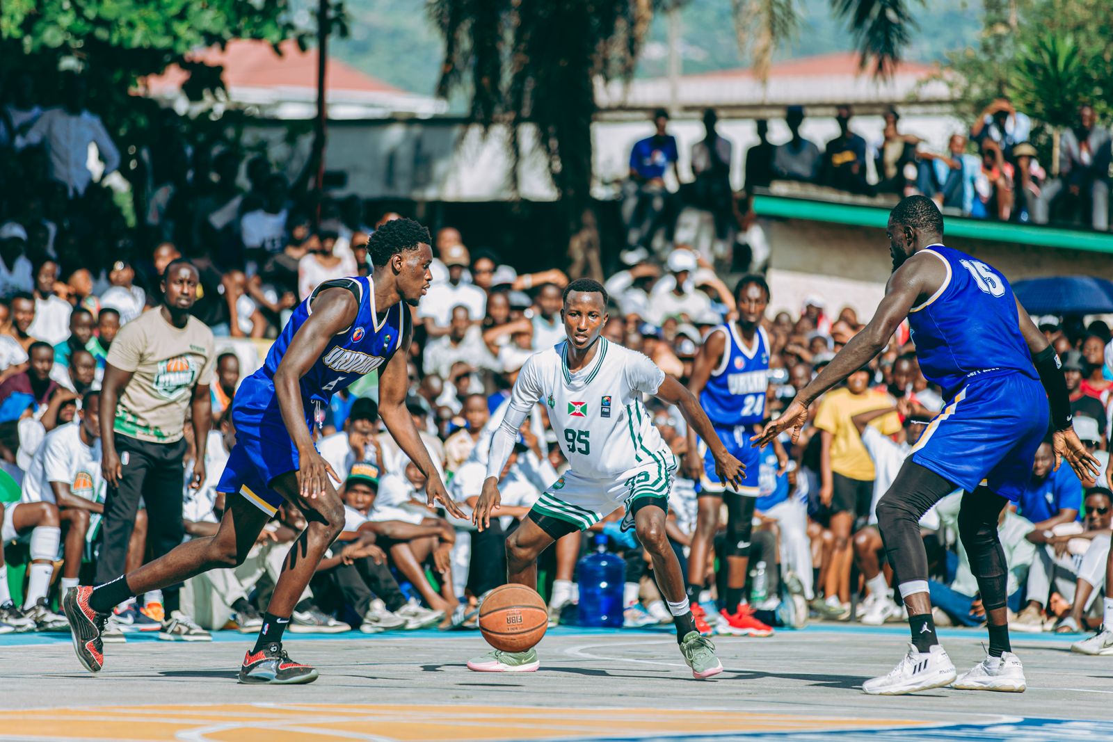 Partida de basquete ao ar livre acompanhada por uma torcida animada ao redor da quadra