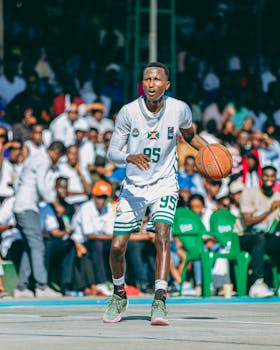 A young male athlete dribbling a basketball during a game on an outdoor court.