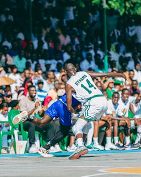 Intense moment of a competitive outdoor basketball game with players in action and a crowd watching.