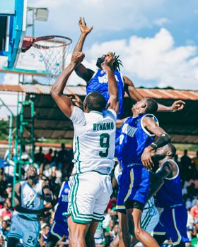Basketball players in action during a competitive outdoor game on a sunny day, showcasing teamwork and athleticism.