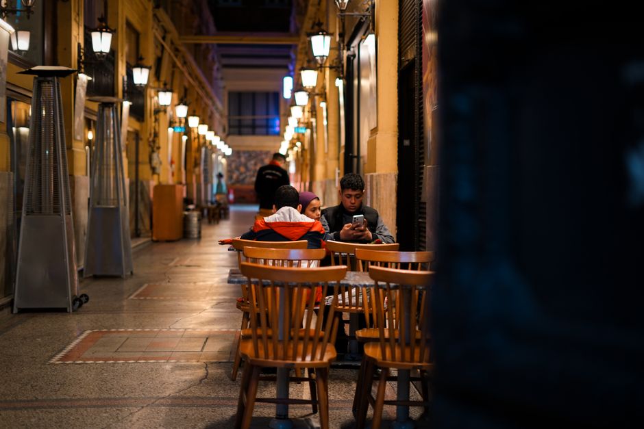 Tres personas disfrutan de una tranquila velada en un acogedor café en un encantador callejón.