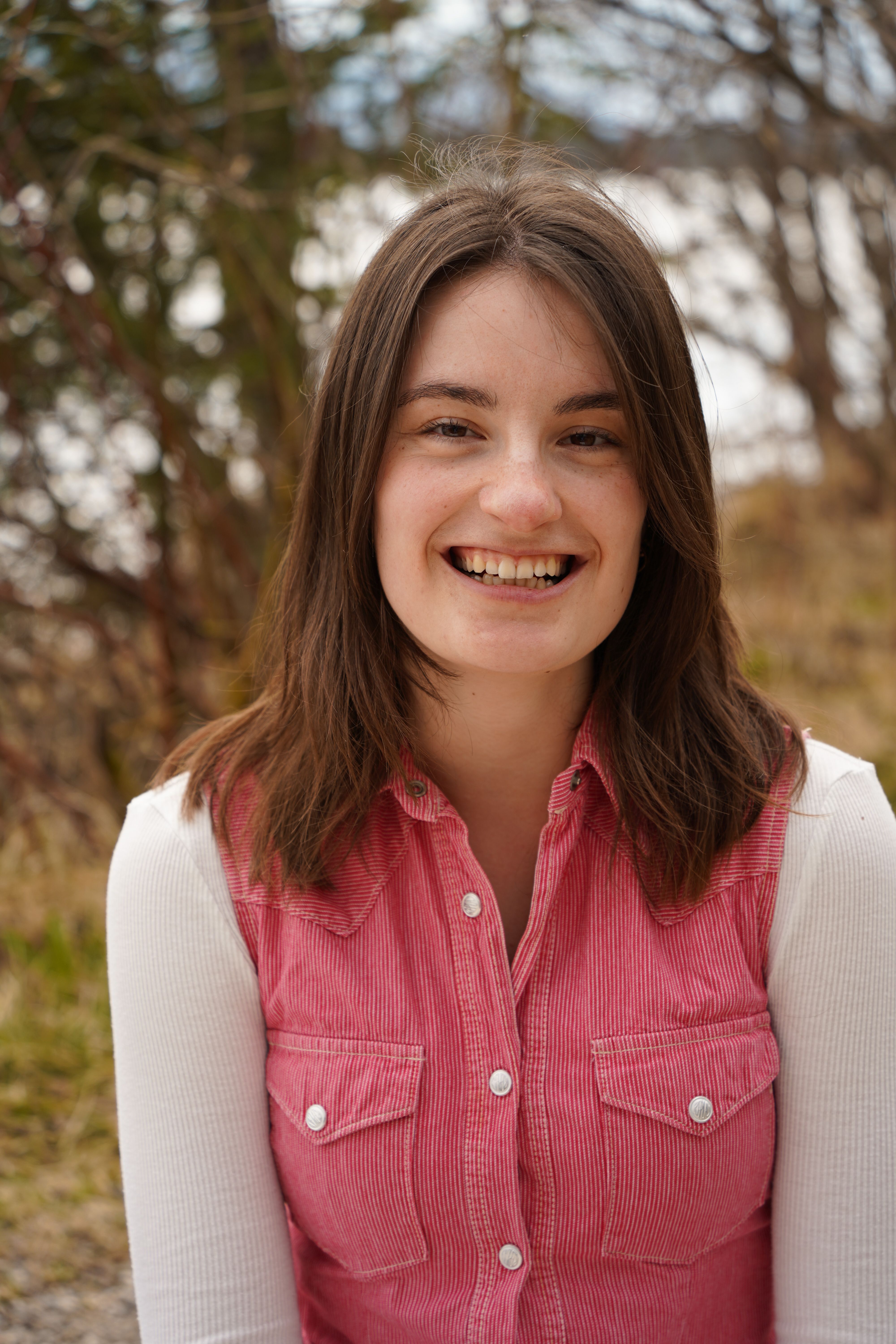 Portrait of a smiling woman in casual clothing outdoors during the day.