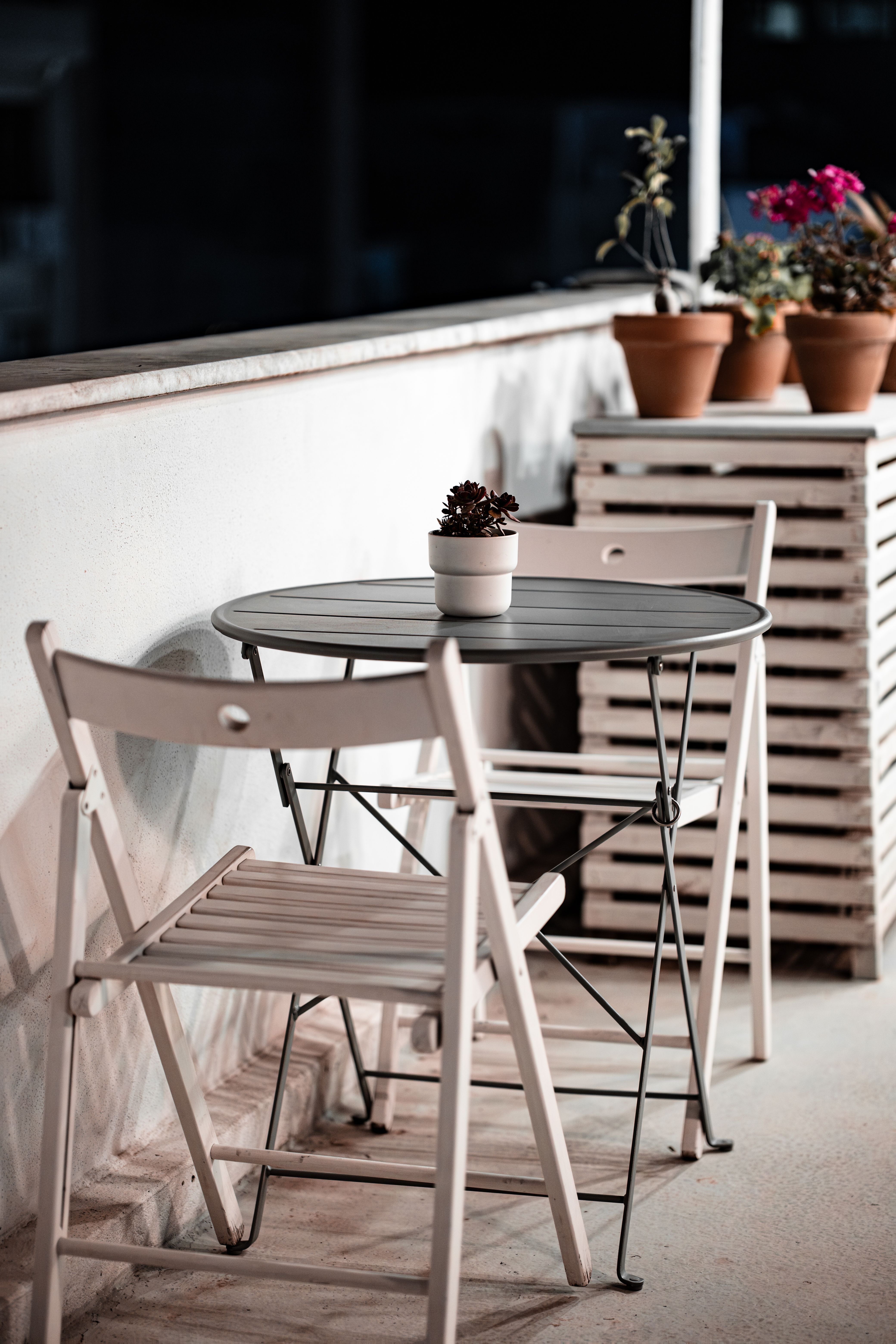 Gray waterproof storage ottoman on a small apartment patio, with a plant sitting on its closed top