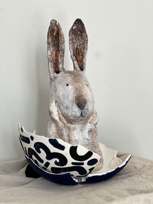 Free A rustic rabbit sculpture emerges from a hand-painted eggshell on a neutral backdrop. Stock Photo