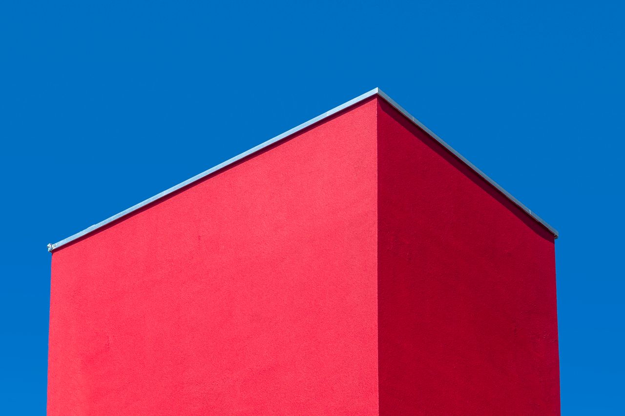 a striking red building facade with a minimalist aesthetic against a c
