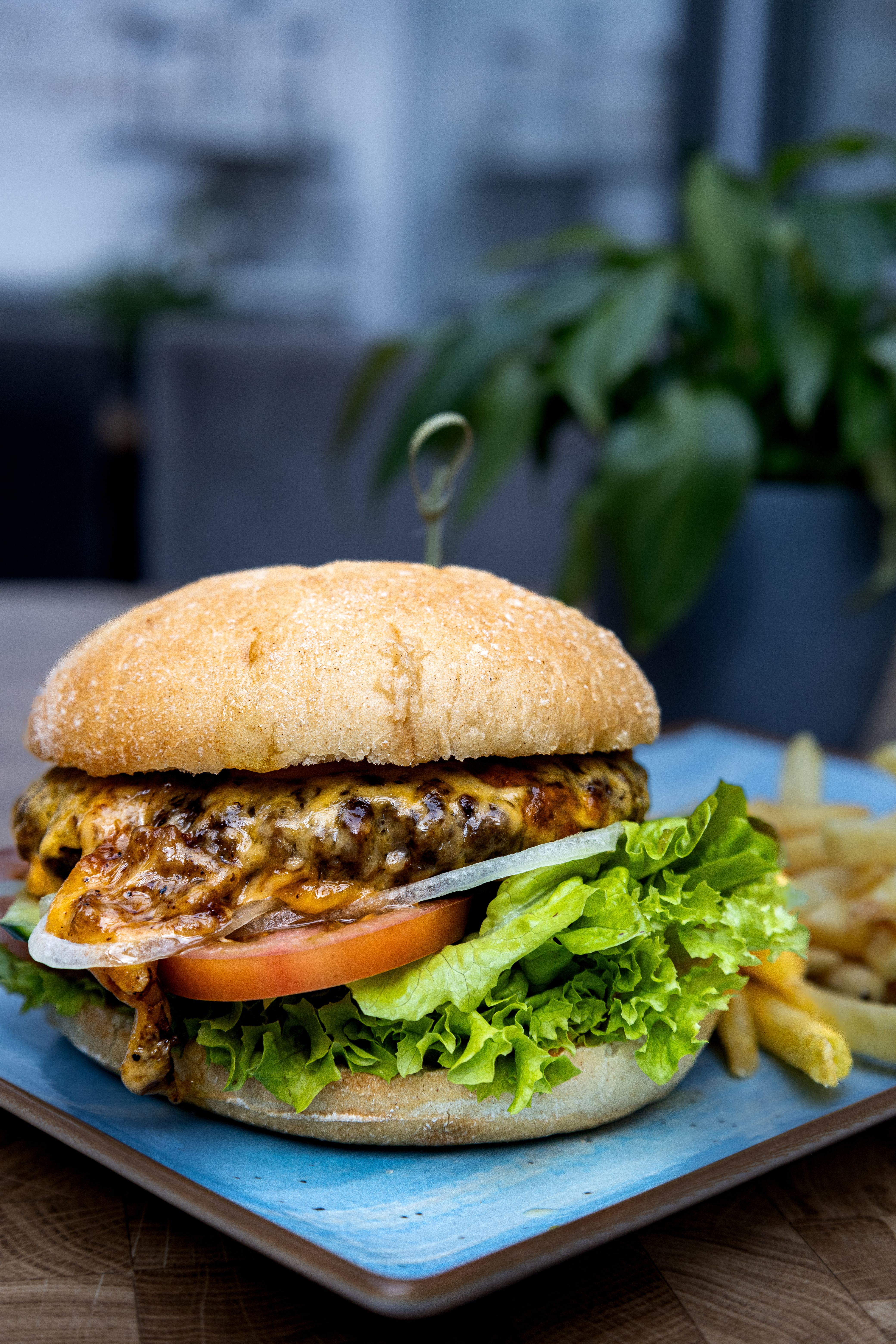 Mouthwatering cheeseburger with fresh lettuce, tomato, and fries on a blue plate, perfect for casual dining.