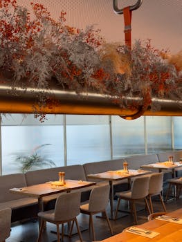 A stylish restaurant interior featuring cozy seating and elegant dried floral arrangements.