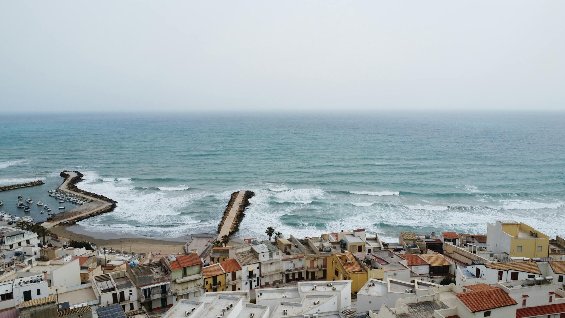 A picturesque coastal town with colorful rooftops overlooking the vast ocean waves.