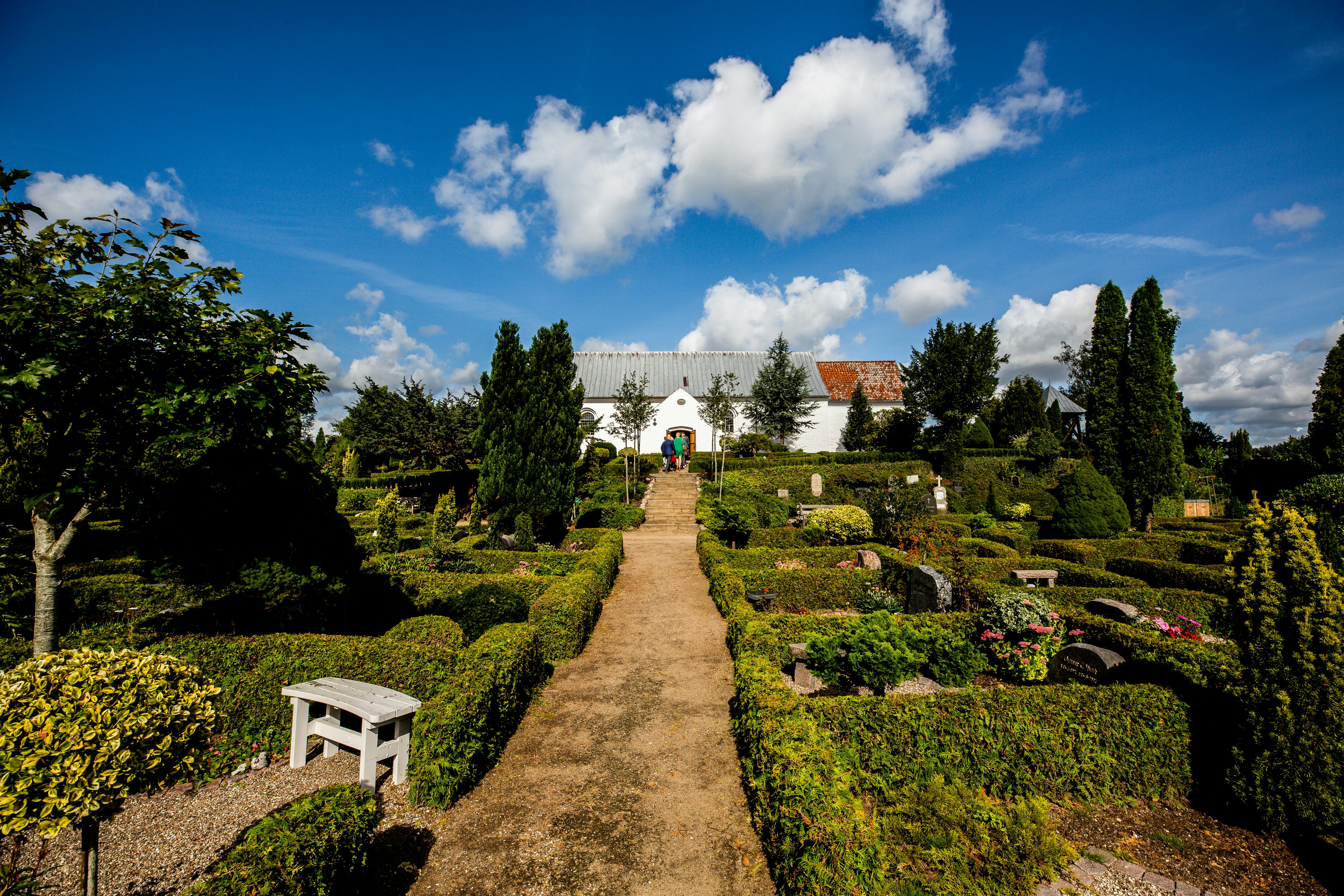 在明亮的蓝天下，一条宁静的花园小路通往一座历史悠久的欧洲教堂