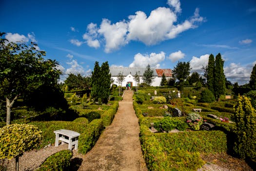 在明亮的蓝天下，一条宁静的花园小路通往一座历史悠久的欧洲教堂