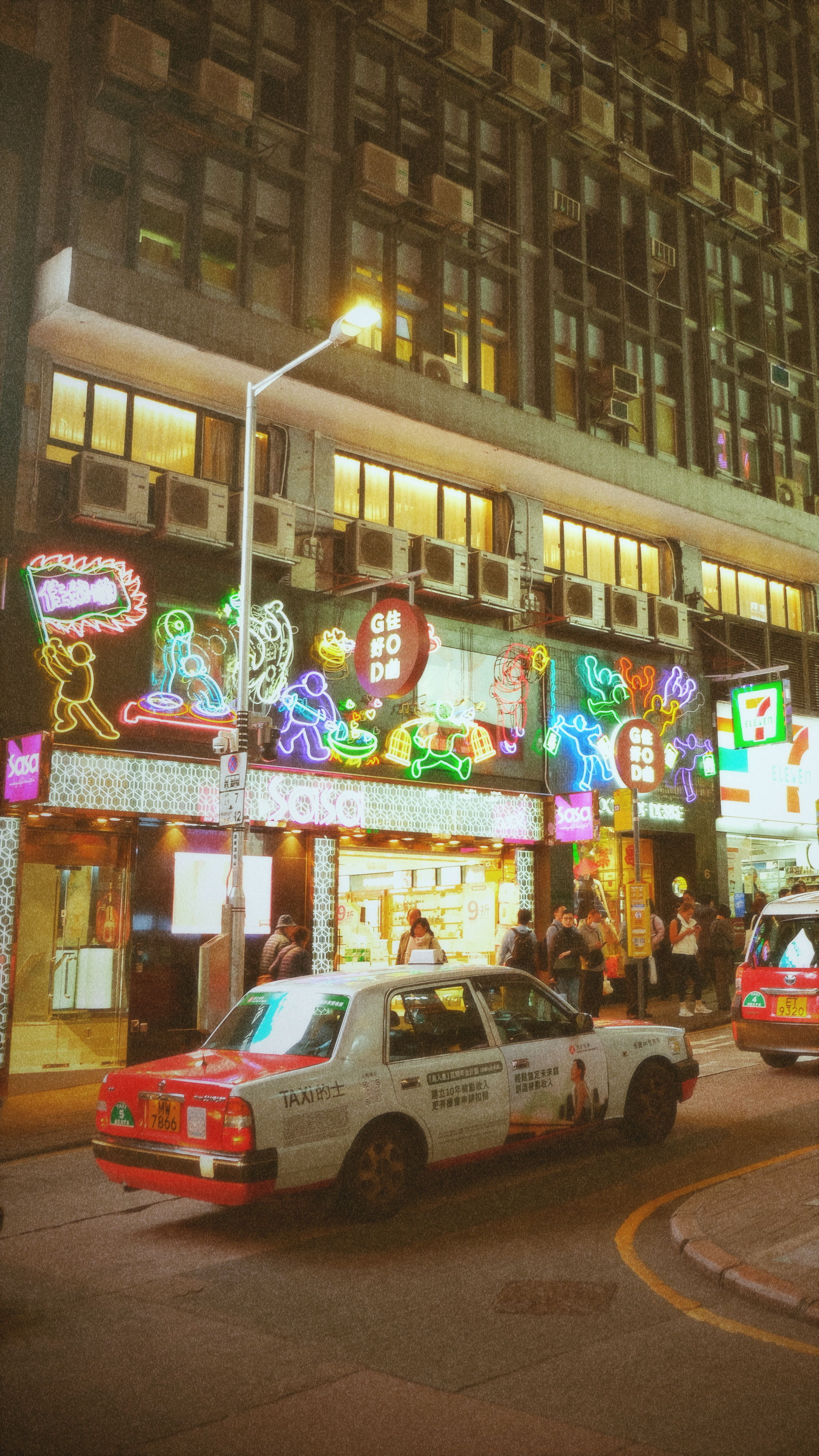 Bustling night street in Hong Kong with vibrant neon signs and iconic taxi. Urban nightlife at its best.