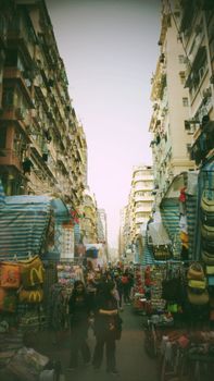 Bustling outdoor market in a city street lined with high-rise buildings.
