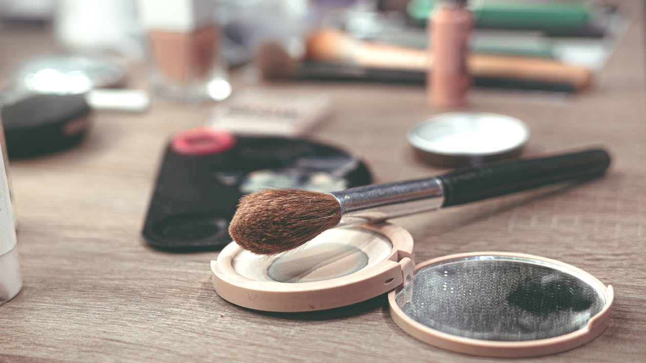 close up of makeup brushes and compact powder