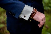 一张展示西装袖子、手镯和戒指的男士手部时尚特写