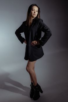 A stylish woman poses confidently in a black jacket, showcasing modern fashion and elegance.