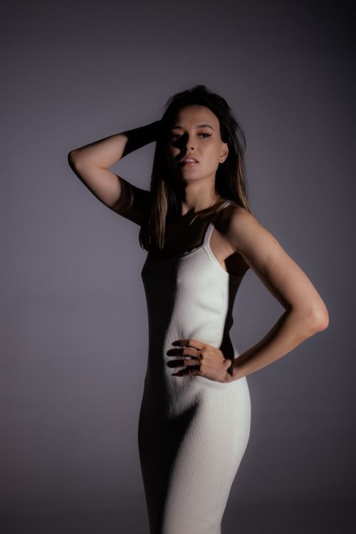 Free Stylish portrait of a woman in a white dress with dramatic lighting, exuding elegance. Stock Photo