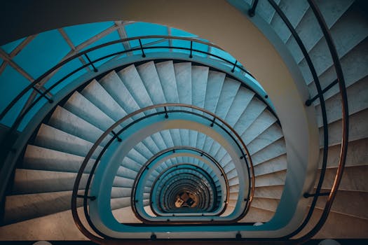 A mesmerizing view of a spiral staircase descending in a modern building, shot from above.