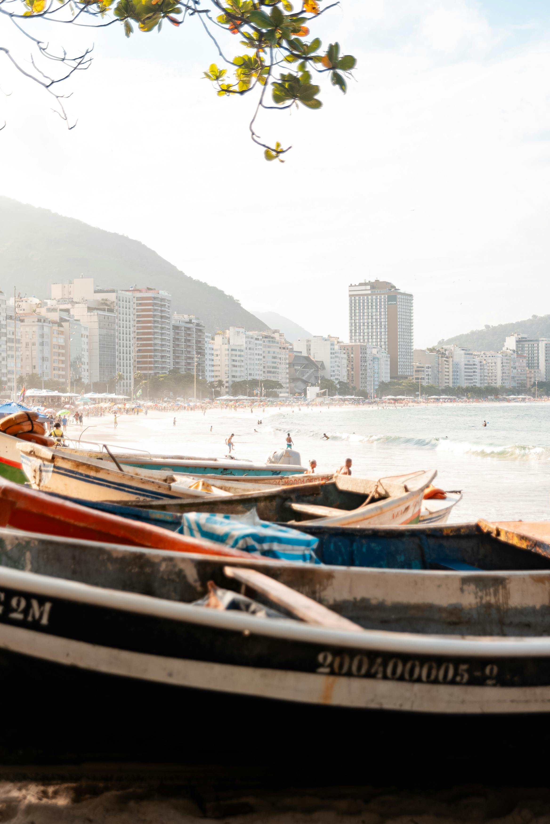 Copacabana Beach with boats, sand, and Rio skyline beyond.