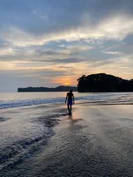A person walking along the tranquil Buenaventura beach during a stunning sunset.