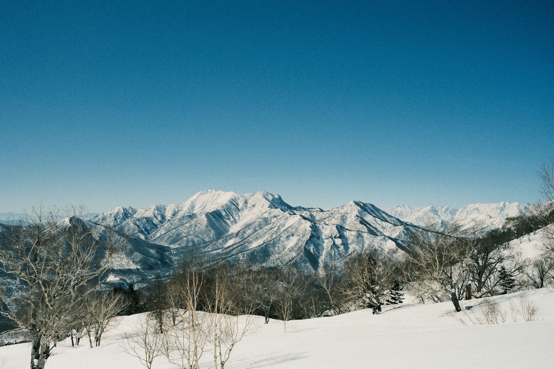 Stunning view of snow-covered mountains with clear blue sky in Japan.