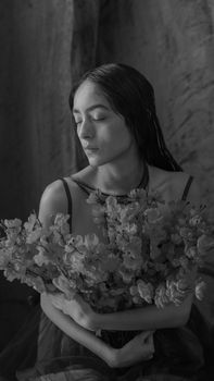 Artistic portrait of a woman holding flowers in black and white. Captivating and timeless.