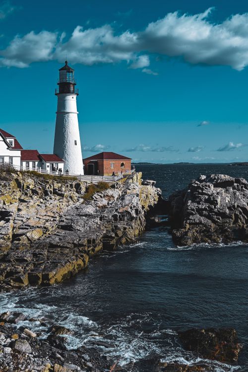 Free Beautiful view of the iconic Portland Head Lighthouse on a rocky Maine coastline with blue skies. Stock Photo