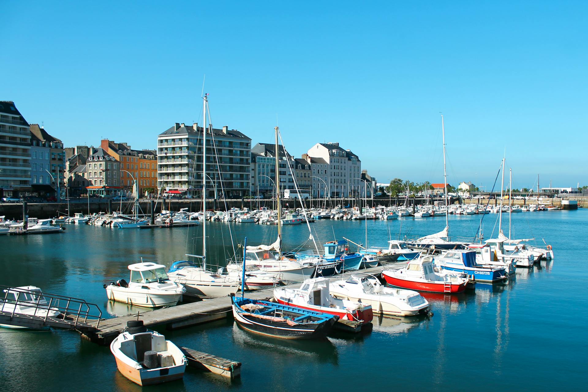 Bright day at Cherbourg Marina, Normandy with boats and colorful buildings along the waterfront.
