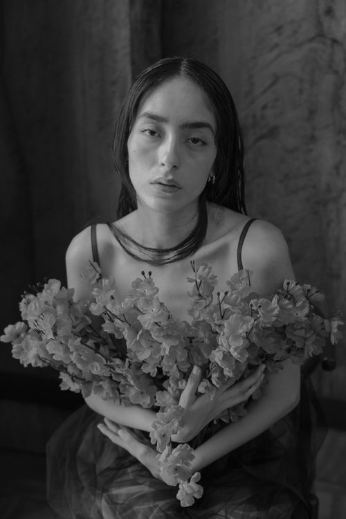 Free Black and white portrait of a woman holding flowers, evoking a moody and artistic vibe. Stock Photo