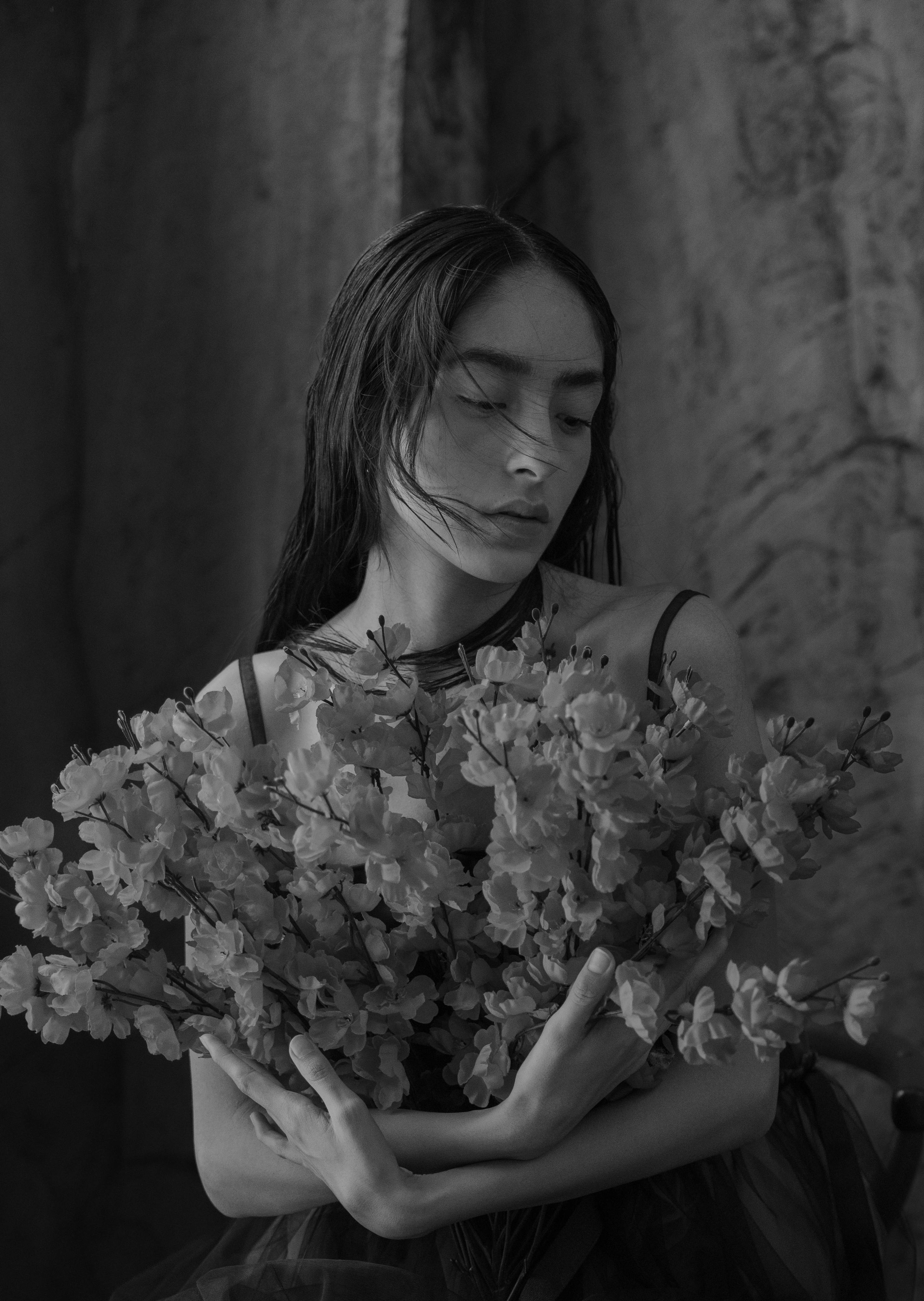 Black and white portrait of a woman holding flowers, exuding a serene mood.