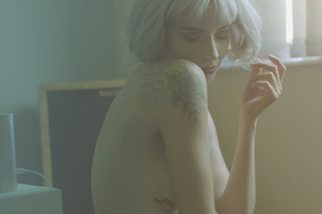 Free Close Of A Naked  Blonde Woman With Tattoos On Her Shoulder And Side Stock Photo