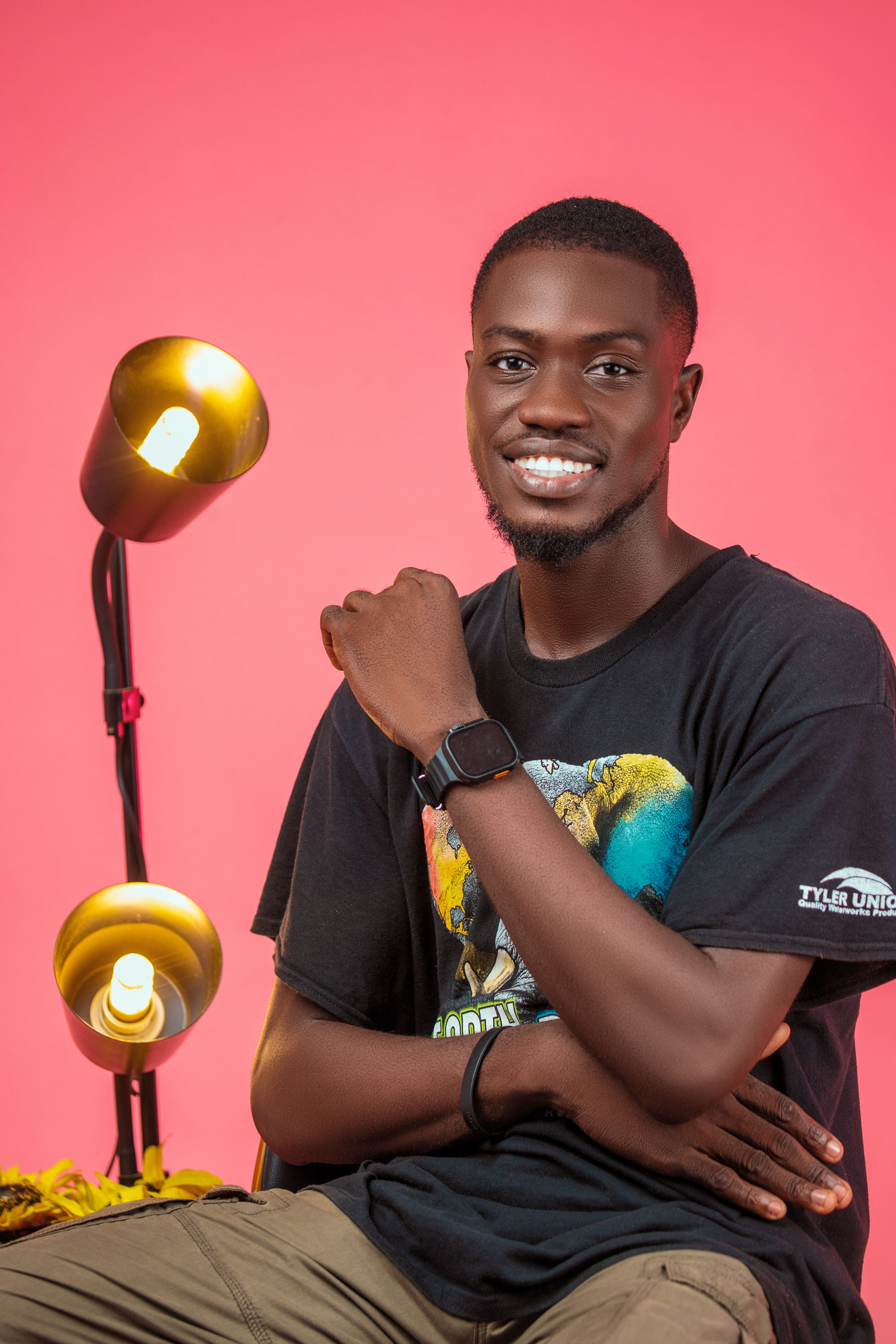Cheerful man in casual graphic t-shirt posing against a vibrant pink studio background.