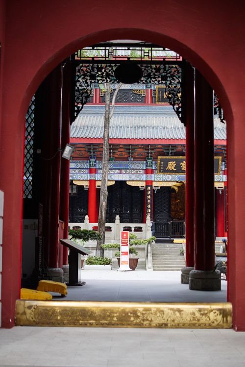 Free View of a traditional Chinese temple through an ornate archway, showcasing intricate architectural details. Stock Photo