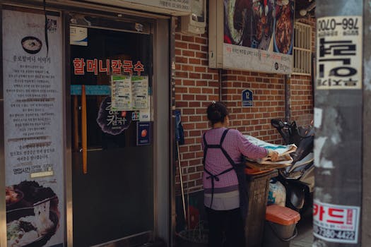 A woman works outside a traditional Korean restaurant in Seoul, capturing local street culture.