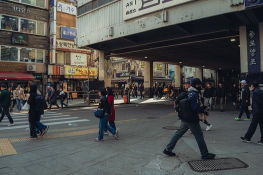Busy urban street in Seoul with pedestrians and traditional Korean signage.