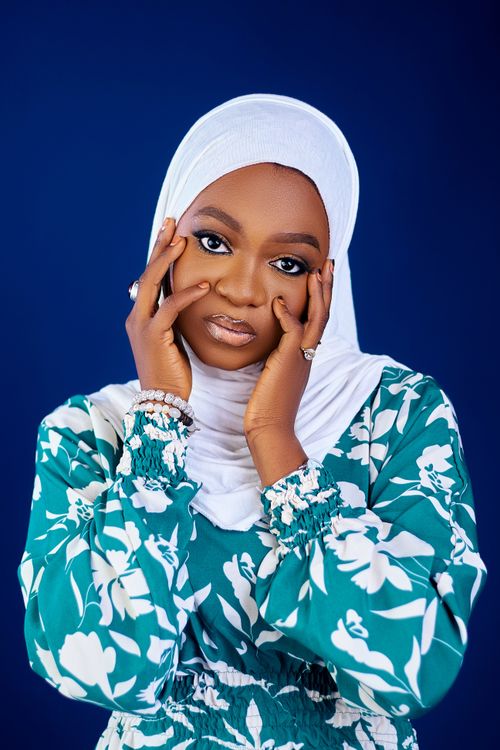 Free Graceful portrait of a woman wearing a floral hijab and dress, epitomizing elegance and confidence. Stock Photo