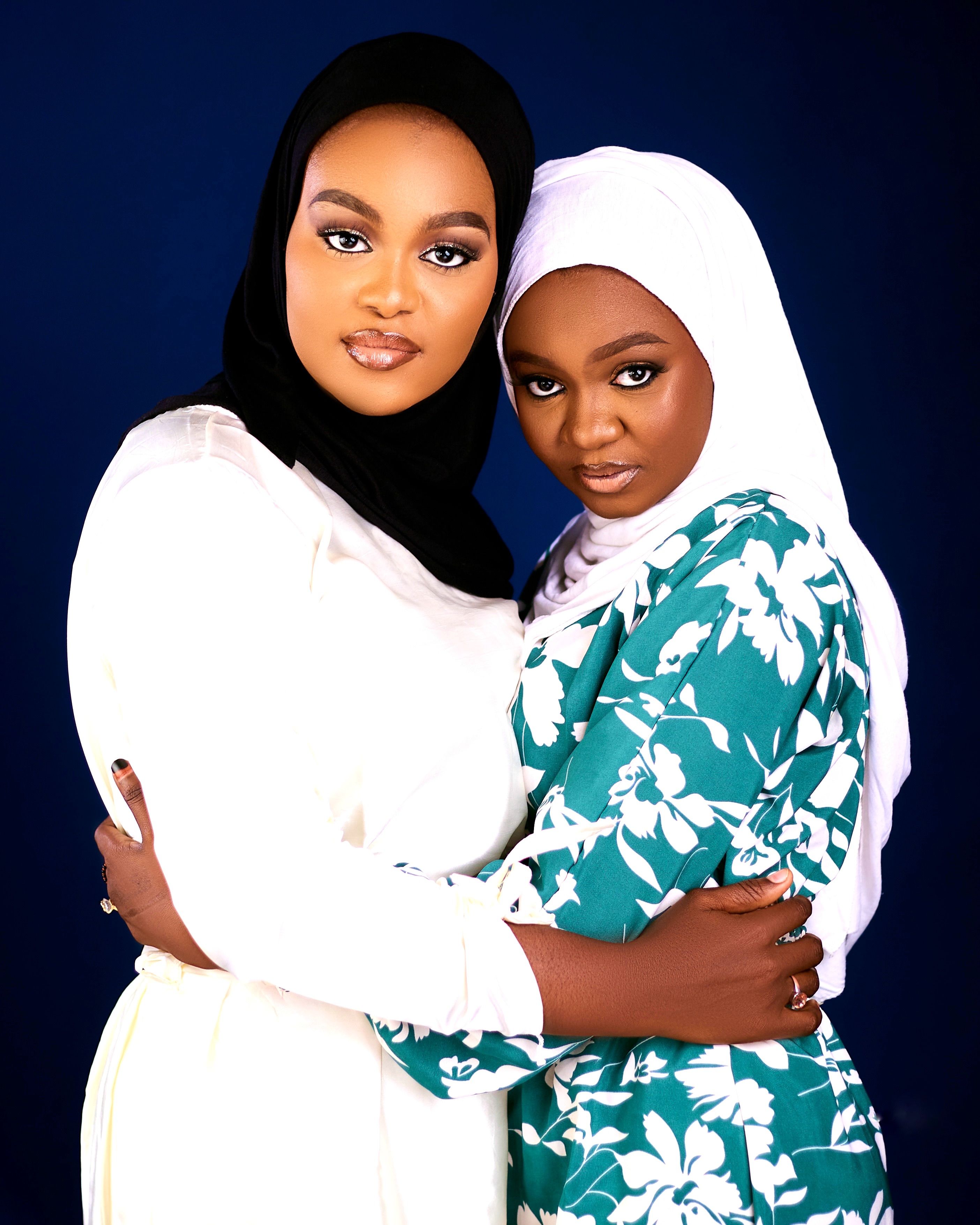 Two women in hijabs embracing, showcasing friendship and cultural fashion.