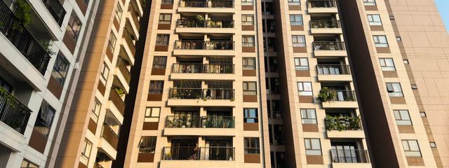 High-rise apartment buildings with balconies in an urban setting under a clear blue sky, emphasizing modern architecture.