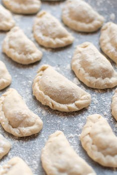 Close-up of homemade dumplings on a floured kitchen surface, ready for cooking.